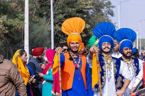 stock image Bikaner, Rajasthan, India - January 2023: Punjabi Bhangra, Portrait of young sikh male in traditional punjabi colorful dress and turban performing bhangra dance with smile in camel festival with focus