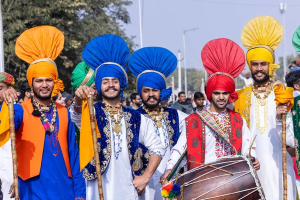 stock image Bikaner, Rajasthan, India - January 2023: Punjabi Bhangra, Portrait of young sikh male in traditional punjabi colorful dress and turban performing bhangra dance with smile in camel festival with focus
