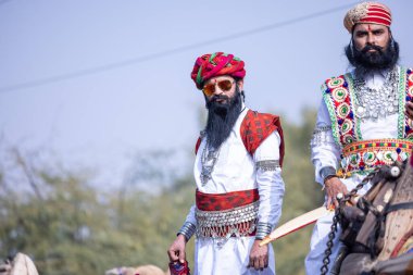 Bikaner, Rajasthan, India - January 2023: Camel Festival, Portrait of an young rajasthani male with beard and moustache wearing white traditional rajasthani dress and turban. Rajput male of bikaner.