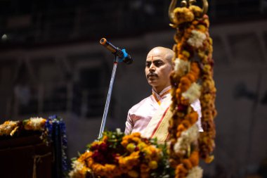 Varanasi, Uttar Pradesh, Hindistan - Kasım 2022: Ganga aarti, genç bir rahibin portresi Daswamedh ghat 'ta akşam üzeri sanatan hindu ayinleriyle geleneksel elbise içinde nehir çetelerini icra ediyor..