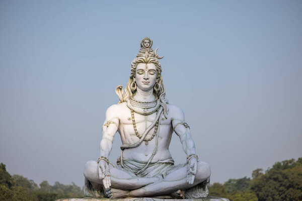 Rishikesh, Uttarakhand, India - October 2022: Lord Shiva, Handmade statue of lord shiv with plain background near river ganges ghat in rishikesh.