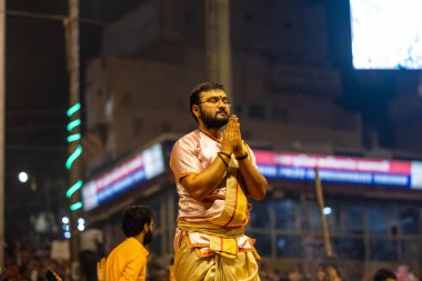 Varanasi, Uttar Pradesh, India - November 2022: Ganga aarti, Portrait of an young priest performing river ganges evening aarti at dasaswamedh ghat in traditional dress with sanatan hindu rituals. clipart