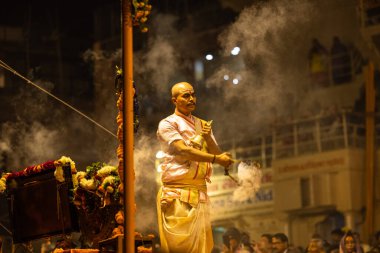 Varanasi, Uttar Pradesh, Hindistan - Kasım 2022: Ganga aarti, Dashashwamedh Ghat 'ta akşamüstü sanatan hindu ayinleriyle geleneksel elbise giymiş genç bir rahibin portresi.