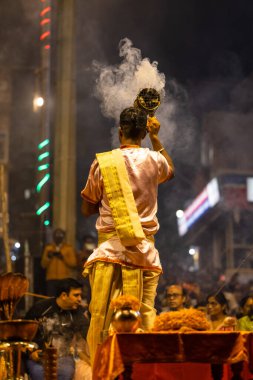 Varanasi, Uttar Pradesh, Hindistan - Kasım 2022: Ganga aarti, Dashashwamedh Ghat 'ta akşamüstü sanatan hindu ayinleriyle geleneksel elbise giymiş genç bir rahibin portresi.