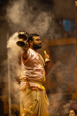 Varanasi, Uttar Pradesh, Hindistan - Kasım 2022: Ganga aarti, Dashashwamedh Ghat 'ta akşamüstü sanatan hindu ayinleriyle geleneksel elbise giymiş genç bir rahibin portresi.