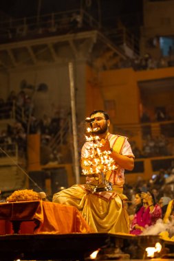 Varanasi, Uttar Pradesh, Hindistan - Kasım 2022: Ganga aarti, Dashashwamedh Ghat 'ta akşamüstü sanatan hindu ayinleriyle geleneksel elbise giymiş genç bir rahibin portresi.