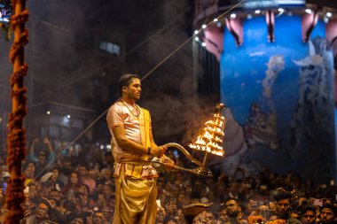 Varanasi, Uttar Pradesh, Hindistan - Kasım 2022: Ganga aarti, Dashashwamedh Ghat 'ta akşamüstü sanatan hindu ayinleriyle geleneksel elbise giymiş genç bir rahibin portresi.