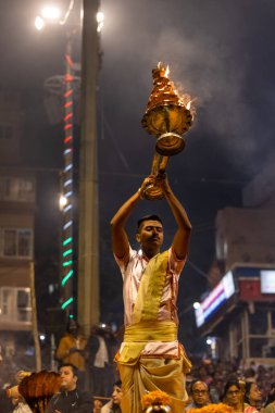 Varanasi, Uttar Pradesh, Hindistan - Kasım 2022: Ganga aarti, Dashashwamedh Ghat 'ta akşamüstü sanatan hindu ayinleriyle geleneksel elbise giymiş genç bir rahibin portresi.