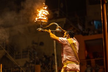 Varanasi, Uttar Pradesh, Hindistan - Kasım 2022: Ganga aarti, Dashashwamedh Ghat 'ta akşamüstü sanatan hindu ayinleriyle geleneksel elbise giymiş genç bir rahibin portresi.