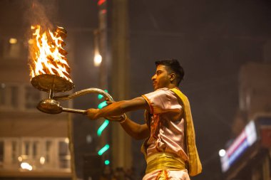 Varanasi, Uttar Pradesh, Hindistan - Kasım 2022: Ganga aarti, Dashashwamedh Ghat 'ta akşamüstü sanatan hindu ayinleriyle geleneksel elbise giymiş genç bir rahibin portresi.