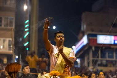 Varanasi, Uttar Pradesh, Hindistan - Kasım 2022: Ganga aarti, Dashashwamedh Ghat 'ta akşamüstü sanatan hindu ayinleriyle geleneksel elbise giymiş genç bir rahibin portresi.