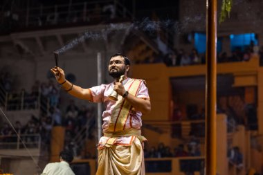 Varanasi, Uttar Pradesh, Hindistan - Kasım 2022: Ganga aarti, Dashashwamedh Ghat 'ta akşamüstü sanatan hindu ayinleriyle geleneksel elbise giymiş genç bir rahibin portresi.