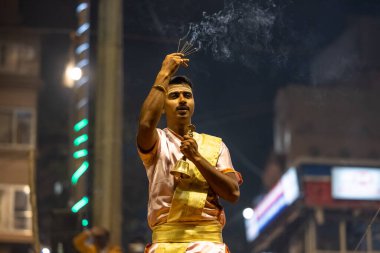 Varanasi, Uttar Pradesh, Hindistan - Kasım 2022: Ganga aarti, Dashashwamedh Ghat 'ta akşamüstü sanatan hindu ayinleriyle geleneksel elbise giymiş genç bir rahibin portresi.