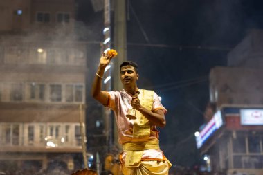 Varanasi, Uttar Pradesh, Hindistan - Kasım 2022: Ganga aarti, Dashashwamedh Ghat 'ta akşamüstü sanatan hindu ayinleriyle geleneksel elbise giymiş genç bir rahibin portresi.