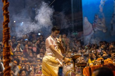 Varanasi, Uttar Pradesh, Hindistan - Kasım 2022: Ganga aarti, Dashashwamedh Ghat 'ta akşamüstü sanatan hindu ayinleriyle geleneksel elbise giymiş genç bir rahibin portresi.