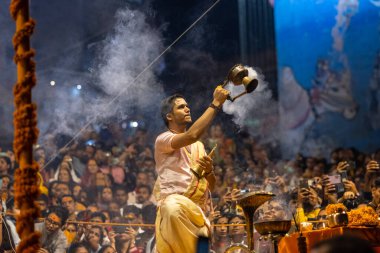 Varanasi, Uttar Pradesh, Hindistan - Kasım 2022: Ganga aarti, Dashashwamedh Ghat 'ta akşamüstü sanatan hindu ayinleriyle geleneksel elbise giymiş genç bir rahibin portresi.