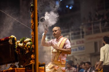 Varanasi, Uttar Pradesh, Hindistan - Kasım 2022: Ganga aarti, Dashashwamedh Ghat 'ta akşamüstü sanatan hindu ayinleriyle geleneksel elbise giymiş genç bir rahibin portresi.