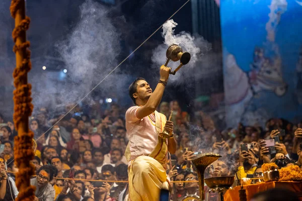 Varanasi, Uttar Pradesh, Hindistan - Kasım 2022: Ganga aarti, Dashashwamedh Ghat 'ta akşamüstü sanatan hindu ayinleriyle geleneksel elbise giymiş genç bir rahibin portresi.