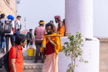 Varanasi, Uttar Pradesh, Hindistan - Kasım 2022: Geleneksel elbise içinde Varanasi şehrinde nehir çetelerinin yanındaki ghat üzerinde yürüyen tanımlanamayan Hint sadhu baba portresi. Varanasi en eski ve kutsal şehirdir..