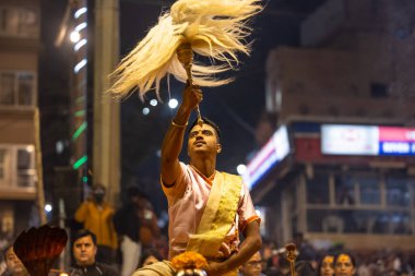 Varanasi, Uttar Pradesh, Hindistan - Kasım 2022: Ganga aarti, Dashashwamedh Ghat 'ta akşamüstü sanatan hindu ayinleriyle geleneksel elbise giymiş genç bir rahibin portresi.