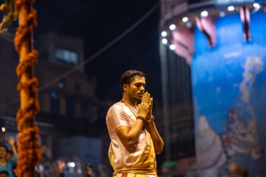 Varanasi, Uttar Pradesh, Hindistan - Kasım 2022: Ganga aarti, Dashashwamedh Ghat 'ta akşamüstü sanatan hindu ayinleriyle geleneksel elbise giymiş genç bir rahibin portresi.