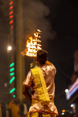Varanasi, Uttar Pradesh, Hindistan - Kasım 2022: Ganga aarti, Dashashwamedh Ghat 'ta akşamüstü sanatan hindu ayinleriyle geleneksel elbise giymiş genç bir rahibin portresi.