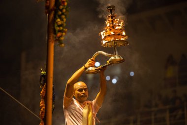 Varanasi, Uttar Pradesh, Hindistan - Kasım 2022: Ganga aarti, Dashashwamedh Ghat 'ta akşamüstü sanatan hindu ayinleriyle geleneksel elbise giymiş genç bir rahibin portresi.