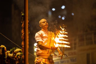 Varanasi, Uttar Pradesh, Hindistan - Kasım 2022: Ganga aarti, Dashashwamedh Ghat 'ta akşamüstü sanatan hindu ayinleriyle geleneksel elbise giymiş genç bir rahibin portresi.