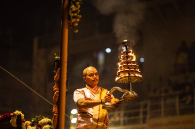 Varanasi, Uttar Pradesh, Hindistan - Kasım 2022: Ganga aarti, Dashashwamedh Ghat 'ta akşamüstü sanatan hindu ayinleriyle geleneksel elbise giymiş genç bir rahibin portresi.