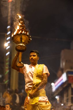 Varanasi, Uttar Pradesh, Hindistan - Kasım 2022: Ganga aarti, Dashashwamedh Ghat 'ta akşamüstü sanatan hindu ayinleriyle geleneksel elbise giymiş genç bir rahibin portresi.