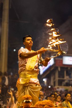 Varanasi, Uttar Pradesh, Hindistan - Kasım 2022: Ganga aarti, Dashashwamedh Ghat 'ta akşamüstü sanatan hindu ayinleriyle geleneksel elbise giymiş genç bir rahibin portresi.