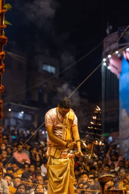 Varanasi, Uttar Pradesh, Hindistan - Kasım 2022: Ganga aarti, Dashashwamedh Ghat 'ta akşamüstü sanatan hindu ayinleriyle geleneksel elbise giymiş genç bir rahibin portresi.