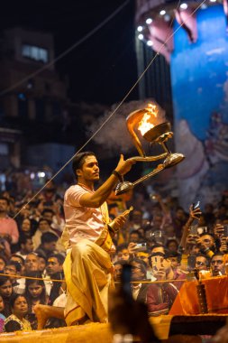 Varanasi, Uttar Pradesh, Hindistan - Kasım 2022: Ganga aarti, Dashashwamedh Ghat 'ta akşamüstü sanatan hindu ayinleriyle geleneksel elbise giymiş genç bir rahibin portresi.