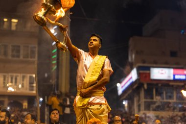 Varanasi, Uttar Pradesh, Hindistan - Kasım 2022: Ganga aarti, Dashashwamedh Ghat 'ta akşamüstü sanatan hindu ayinleriyle geleneksel elbise giymiş genç bir rahibin portresi.
