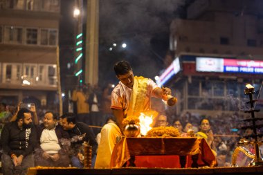 Varanasi, Uttar Pradesh, Hindistan - Kasım 2022: Ganga aarti, Dashashwamedh Ghat 'ta akşamüstü sanatan hindu ayinleriyle geleneksel elbise giymiş genç bir rahibin portresi.