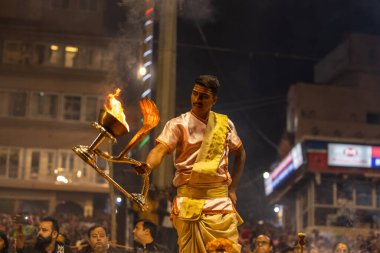 Varanasi, Uttar Pradesh, India - November 2022: Ganga aarti, Portrait of an young priest performing river ganges evening aarti at Dashashwamedh Ghat in traditional dress with sanatan hindu rituals. clipart