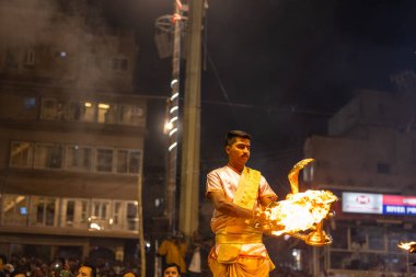 Varanasi, Uttar Pradesh, Hindistan - Kasım 2022: Ganga aarti, Dashashwamedh Ghat 'ta akşamüstü sanatan hindu ayinleriyle geleneksel elbise giymiş genç bir rahibin portresi.