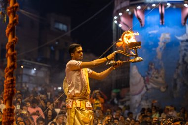 Varanasi, Uttar Pradesh, Hindistan - Kasım 2022: Ganga aarti, Dashashwamedh Ghat 'ta akşamüstü sanatan hindu ayinleriyle geleneksel elbise giymiş genç bir rahibin portresi.