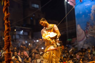 Varanasi, Uttar Pradesh, Hindistan - Kasım 2022: Ganga aarti, Dashashwamedh Ghat 'ta akşamüstü sanatan hindu ayinleriyle geleneksel elbise giymiş genç bir rahibin portresi.