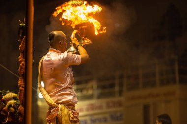 Varanasi, Uttar Pradesh, Hindistan - Kasım 2022: Ganga aarti, Dashashwamedh Ghat 'ta akşamüstü sanatan hindu ayinleriyle geleneksel elbise giymiş genç bir rahibin portresi.