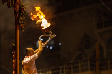 Varanasi, Uttar Pradesh, Hindistan - Kasım 2022: Ganga aarti, Dashashwamedh Ghat 'ta akşamüstü sanatan hindu ayinleriyle geleneksel elbise giymiş genç bir rahibin portresi.