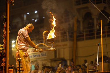 Varanasi, Uttar Pradesh, Hindistan - Kasım 2022: Ganga aarti, Dashashwamedh Ghat 'ta akşamüstü sanatan hindu ayinleriyle geleneksel elbise giymiş genç bir rahibin portresi.