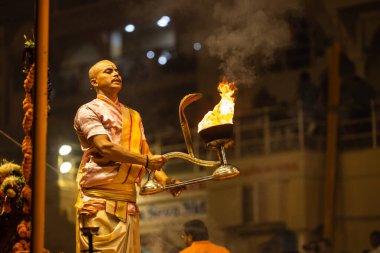 Varanasi, Uttar Pradesh, Hindistan - Kasım 2022: Ganga aarti, Dashashwamedh Ghat 'ta akşamüstü sanatan hindu ayinleriyle geleneksel elbise giymiş genç bir rahibin portresi.
