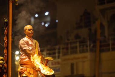 Varanasi, Uttar Pradesh, Hindistan - Kasım 2022: Ganga aarti, Dashashwamedh Ghat 'ta akşamüstü sanatan hindu ayinleriyle geleneksel elbise giymiş genç bir rahibin portresi.