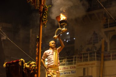 Varanasi, Uttar Pradesh, Hindistan - Kasım 2022: Ganga aarti, Dashashwamedh Ghat 'ta akşamüstü sanatan hindu ayinleriyle geleneksel elbise giymiş genç bir rahibin portresi.