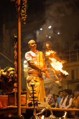 Varanasi, Uttar Pradesh, Hindistan - Kasım 2022: Ganga aarti, Dashashwamedh Ghat 'ta akşamüstü sanatan hindu ayinleriyle geleneksel elbise giymiş genç bir rahibin portresi.