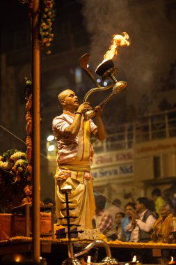 Varanasi, Uttar Pradesh, Hindistan - Kasım 2022: Ganga aarti, Dashashwamedh Ghat 'ta akşamüstü sanatan hindu ayinleriyle geleneksel elbise giymiş genç bir rahibin portresi.