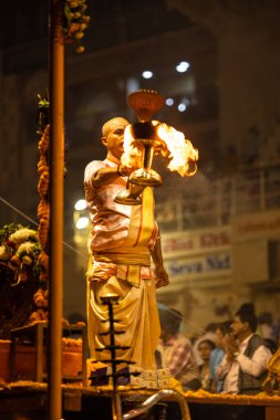 Varanasi, Uttar Pradesh, Hindistan - Kasım 2022: Ganga aarti, Dashashwamedh Ghat 'ta akşamüstü sanatan hindu ayinleriyle geleneksel elbise giymiş genç bir rahibin portresi.