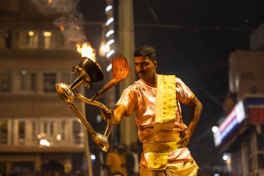 Varanasi, Uttar Pradesh, Hindistan - Kasım 2022: Ganga aarti, Dashashwamedh Ghat 'ta akşamüstü sanatan hindu ayinleriyle geleneksel elbise giymiş genç bir rahibin portresi.