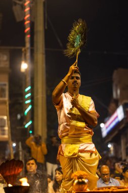 Varanasi, Uttar Pradesh, Hindistan - Kasım 2022: Ganga aarti, Dashashwamedh Ghat 'ta akşamüstü sanatan hindu ayinleriyle geleneksel elbise giymiş genç bir rahibin portresi.